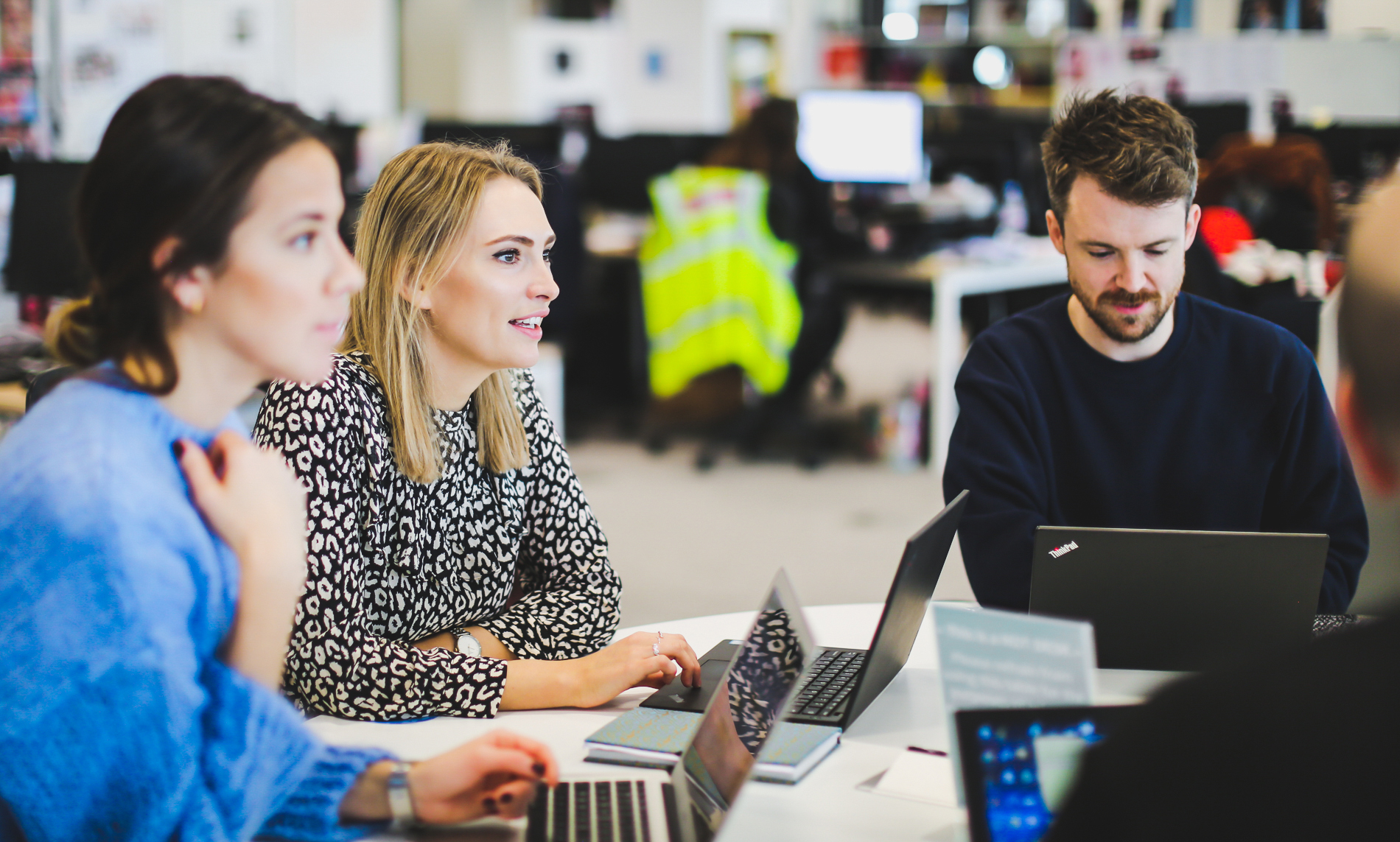 Group of three colleagues, sitting together in a meeting room, having a discussion