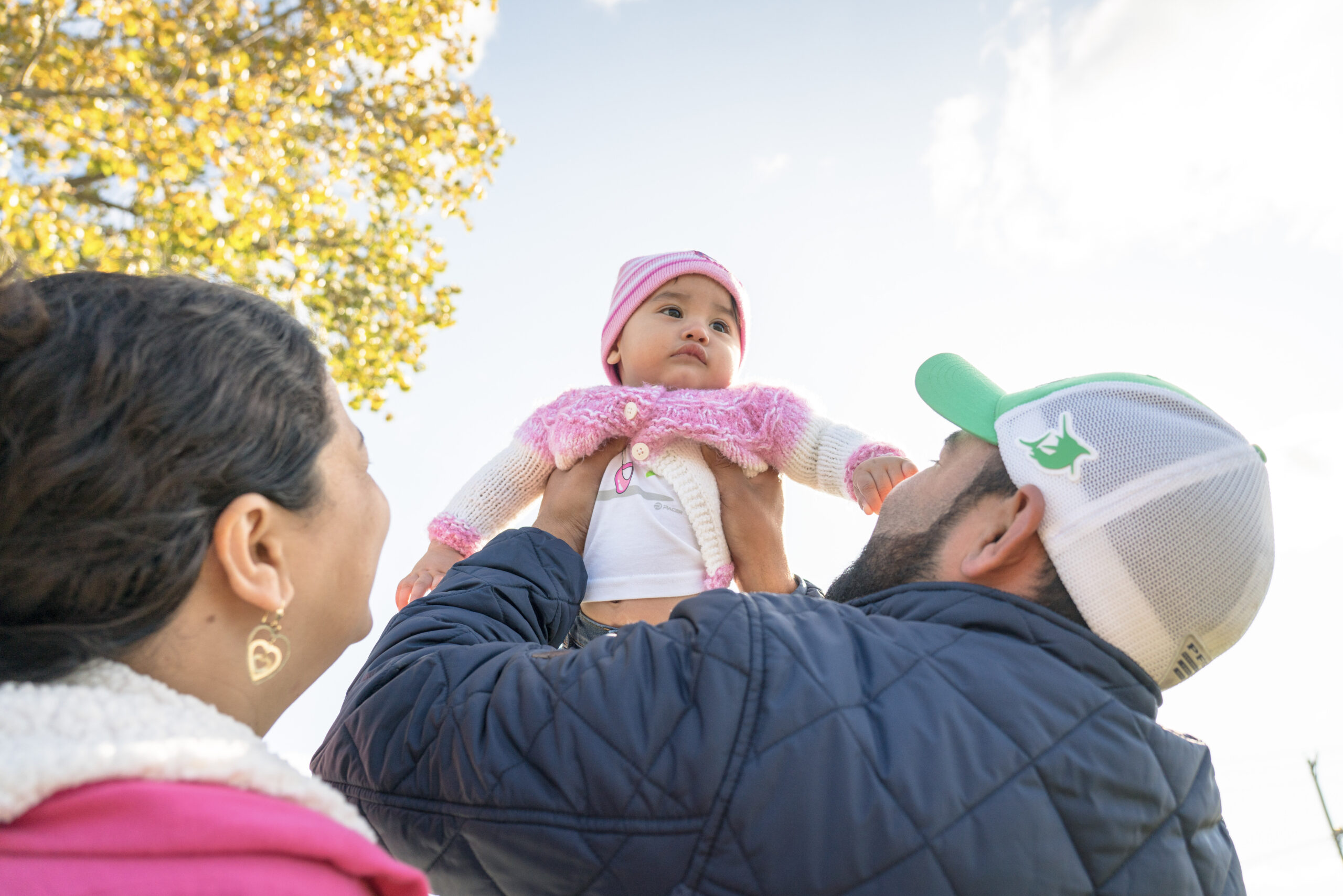 man and woman lifting up baby