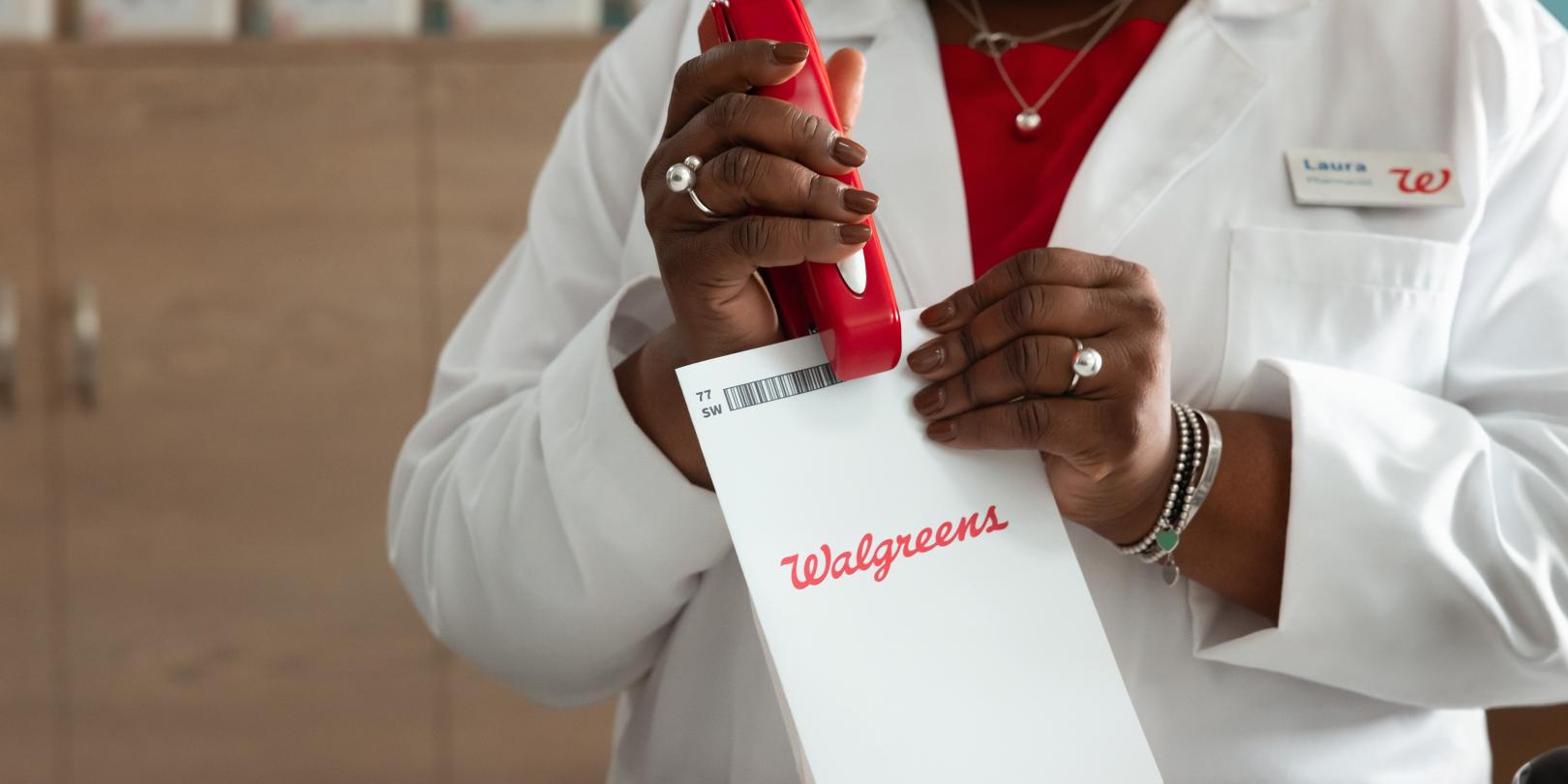 Pharmacist stapling a Walgreens prescription bag