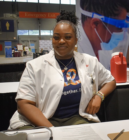 pharmacy intern smiling next to blood pressure machine